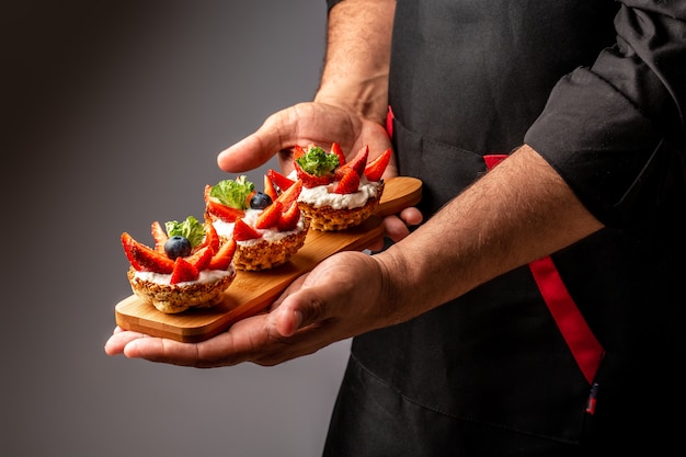 Chef-kok kooktaartjes met room, aardbeien en bosbessen