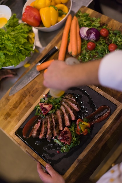 Chef-kok maakt steak vleesbord af met Eindelijk schoteldressing en bijna klaar om te serveren aan het tafelblad