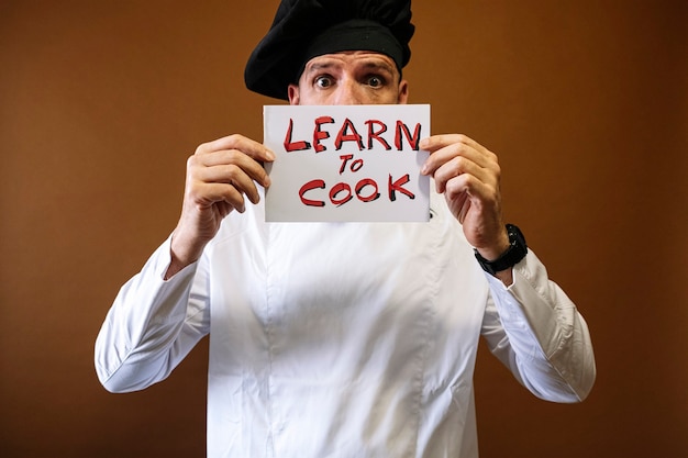 Chef-kok man met een bordje dat zegt: leren en koken