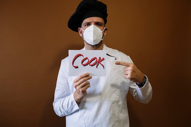 Chef-kok met gezichtsmasker en een bord met de tekst kok