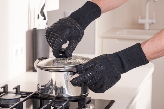 Chef-kok met hete pan in beschermende handschoenen