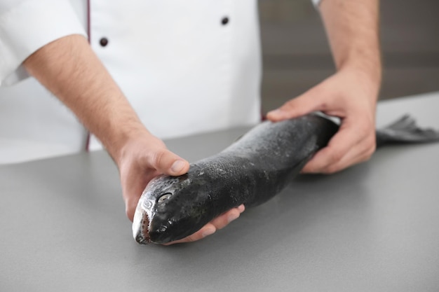 Chef-kok met verse zalm in de keuken