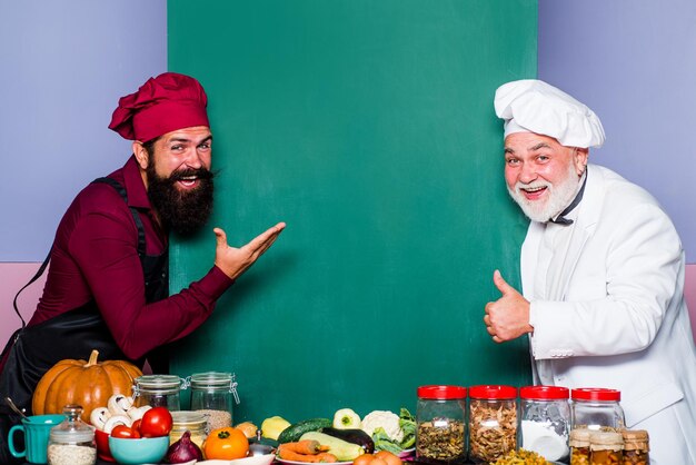 Chef-kok of bakker door leeg schoolbordmenu keuken chef-kok chef-kok die op leeg bord laat zien