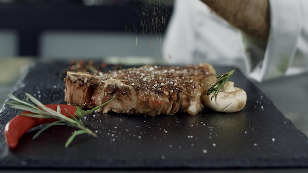 Chef-kok pepert gegrild vlees op snijplank Man overhandigt peperbiefstuk in slow motion