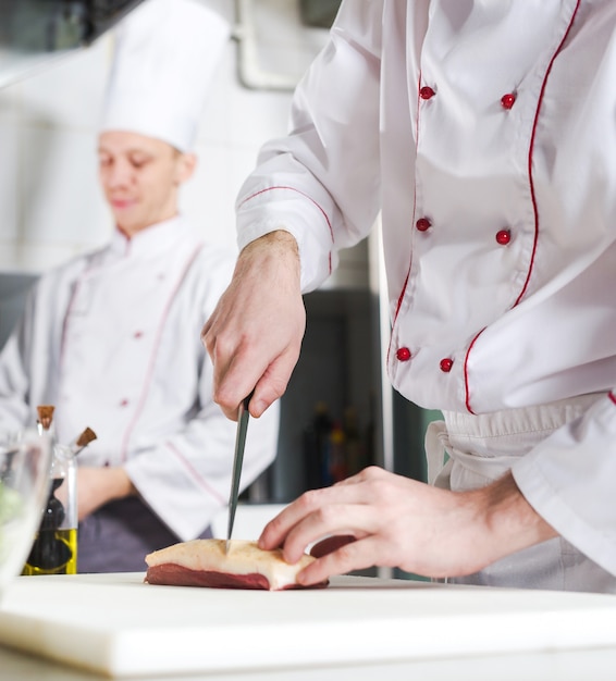 Chef-kok scherp vlees op hakbord, het professionele mes van de kokholding en scherp vlees in restaurant