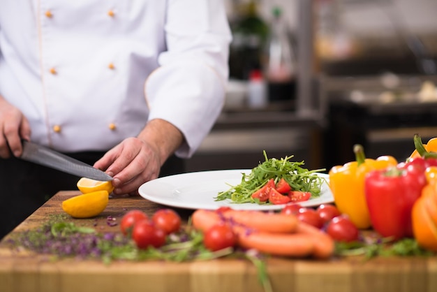 Chef-kok serveert groentesalade op bord in de keuken van het restaurant