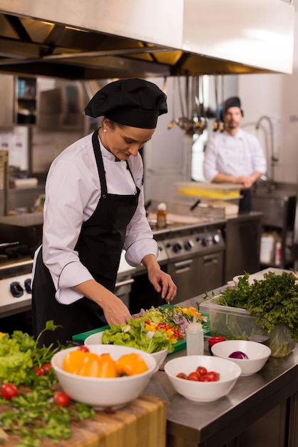 chef-kok serveert groentesalade op bord in de keuken van het restaurant