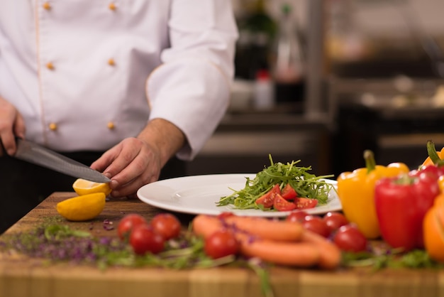 chef-kok serveert groentesalade op bord in de keuken van het restaurant