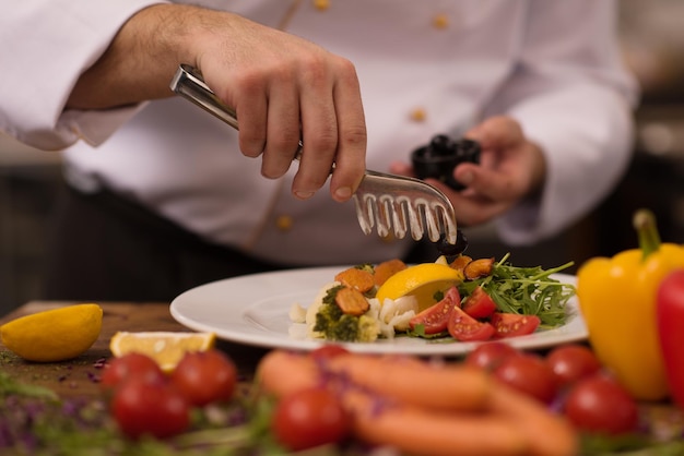 chef-kok serveert groentesalade op bord in de keuken van het restaurant