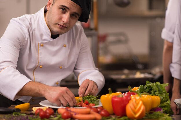 chef-kok serveert groentesalade op bord in de keuken van het restaurant