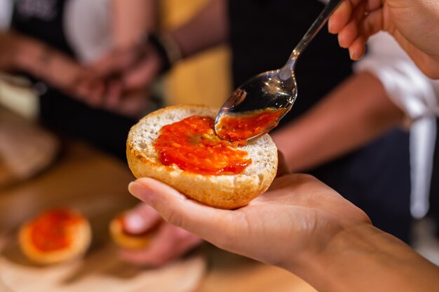 Foto chef-kok smeert een broodje met ketchup voor hamburger close-up eten en koken concept