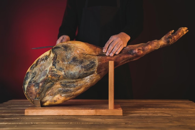 Foto chef-kok snijden ham met mes op een rode achtergrond