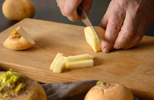 Chef-kok snijdt gele raap voor het koken van gezond veganistisch eten