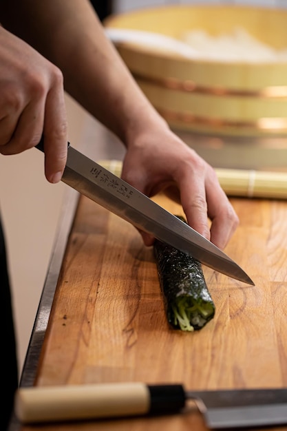 Foto chef-kok snijdt sushi met komkommer.