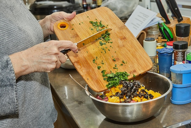 Chef-kok verschuift de greens in een salade met courgettesinaasappelen en salami Franse gastronomische keuken op een houten achtergrond