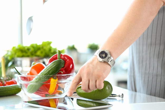 Chef-kok volgens recept op digitale tablet die groentesalade in keuken voorbereidt