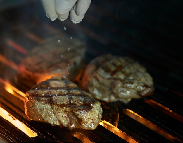 Chef-kok zout toe te voegen aan centrum van gegrilde steak met vlammen en rook