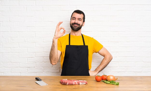 Chef-kokholding in een keuken die ok teken met vingers tonen