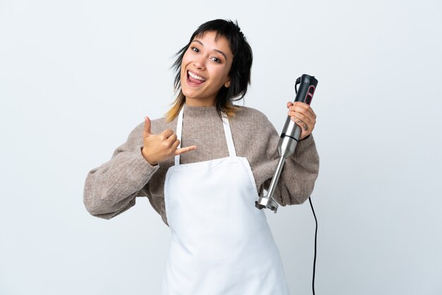 Chef-kokvrouw die handmixer over geïsoleerde witte ruimte gebruiken die telefoongebaar maken