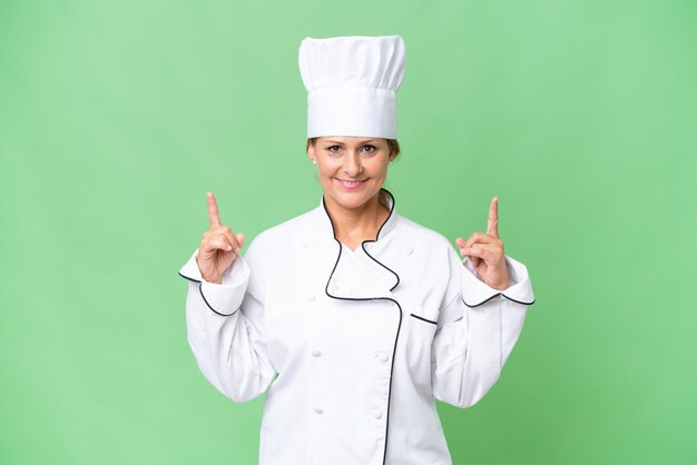 Chef-kokvrouw van middelbare leeftijd over geïsoleerde achtergrond die een geweldig idee benadrukt