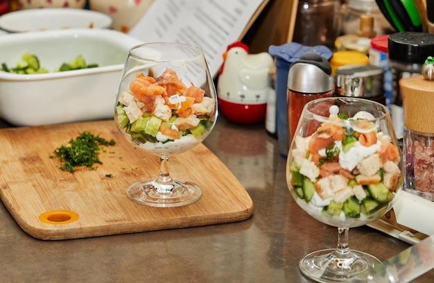 Chef maakt zomersalade in een glas zalm komkommers croutons kruiden en verse room elegante zomer fusion