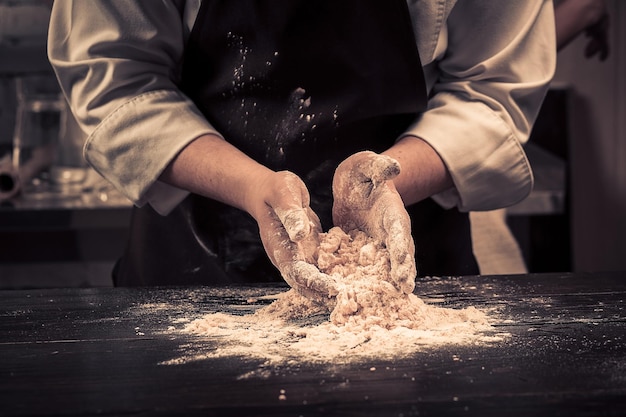 Шеф-повар делает тесто для макарон на деревянном столе