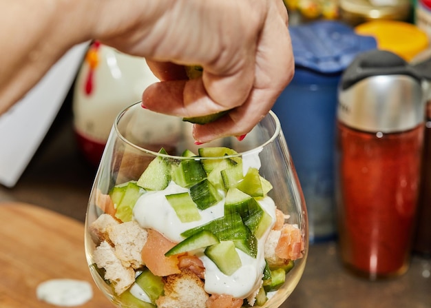 Foto lo chef fa l'insalata estiva in un bicchiere di salmone cetrioli croutoni erbe e crema fresca elegante fusione estiva