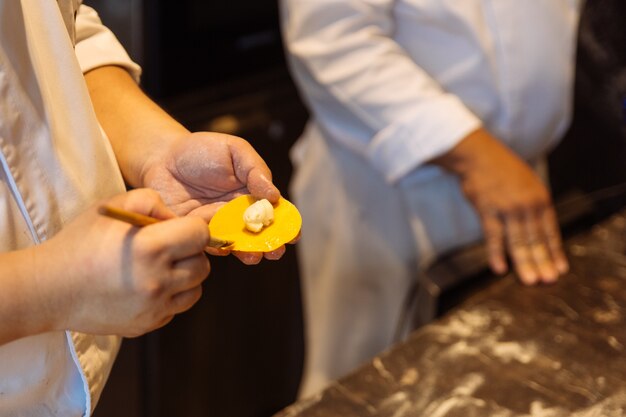 Chef making circle shape Ravioli by filling sage and butter on pasta dough.