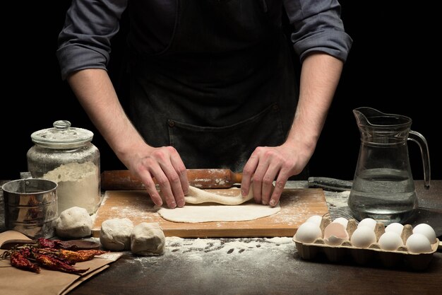 Foto cuoco unico che fa la pasta sulla tavola di legno