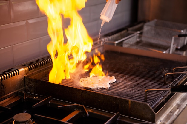 Chef making flambe chicken breast in restaurant kitchen