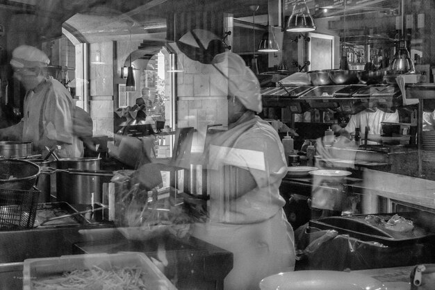 Photo chef making food in kitchen seen through window