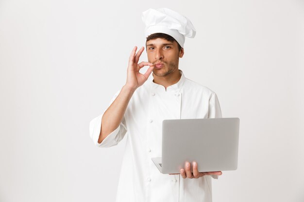 Chef man isolated on white wall using laptop computer.