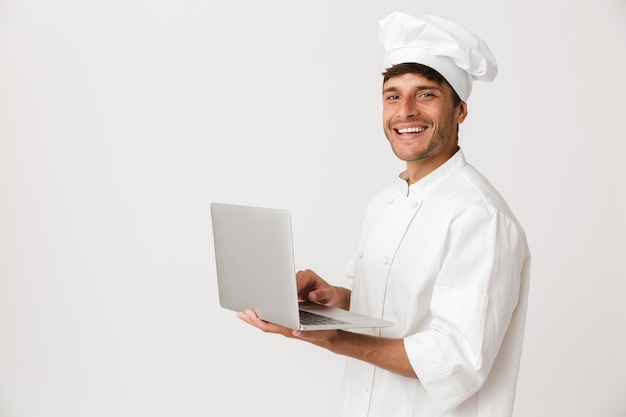 랩톱 컴퓨터를 사용하여 흰 벽에 고립 된 요리사 남자.