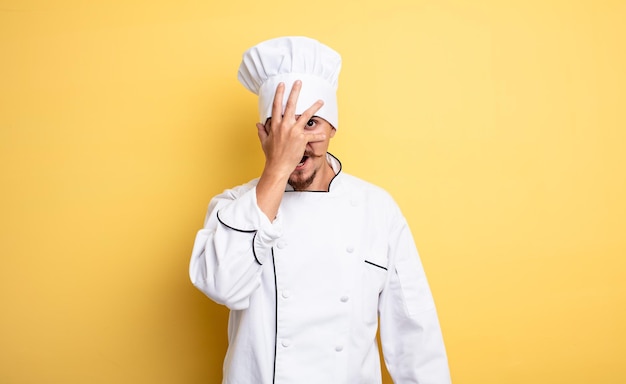 Chef man looking shocked, scared or terrified, covering face with hand