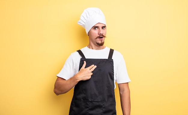 Chef man looking shocked and surprised with mouth wide open pointing to self