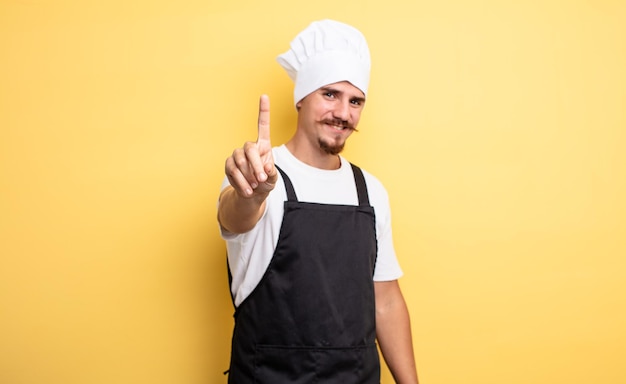 Chef man smiling proudly and confidently making number one