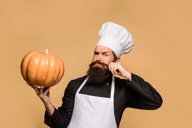 Chef man in white apron presenting pumpkin for culinary thanksgiving seasonal cooking ingredients