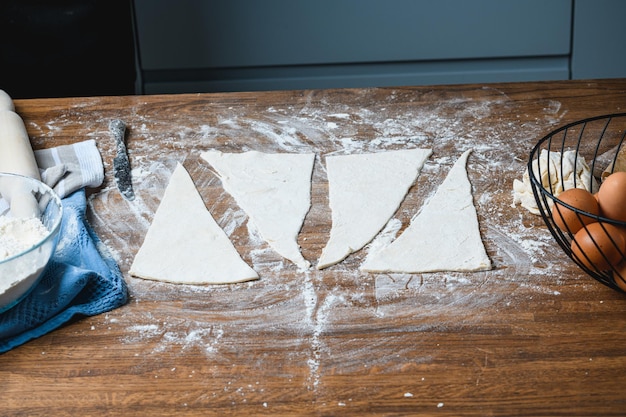 The chef manually makes croissants on the table with ingredients.