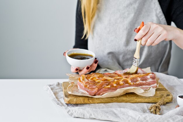 Chef marinating pork ribs in barbecue sauce. 