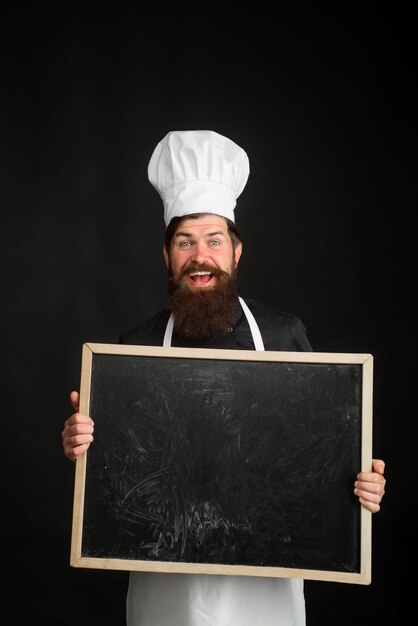 Chef menu master chef baker or cook shows menu sign blackboard professional chef on kitchen empty