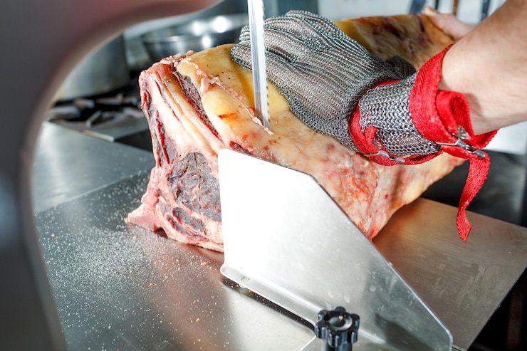 Photo a chef in a metal glove cuts an wetaged ahd dryaged on an electric knife