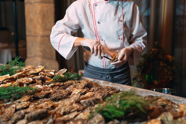 Foto lo chef apre le ostriche nel ristorante