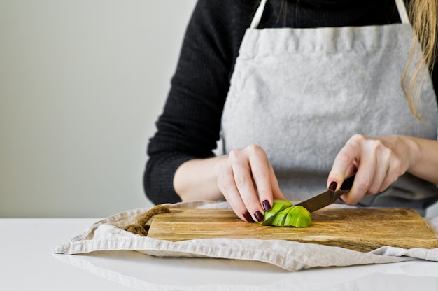 The chef peels avocado on a wooden chopping Board. 