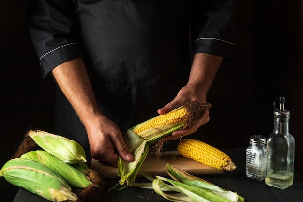 The chef peels ripe corn from shell before cooking Working environment in the restaurant kitchen