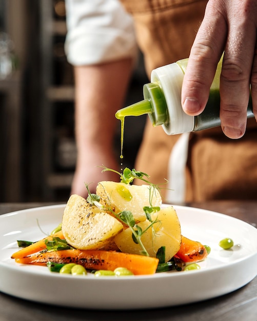 Chef pouring gourmet healthy dish with green sauce