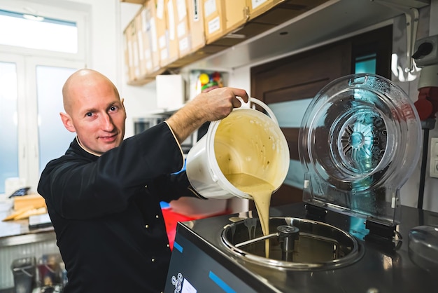 Chef pouring ice cream into ice cream into big steel ice cream machine production concept bald