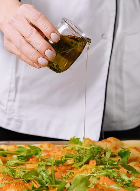 Chef pouring olive oil on pizza