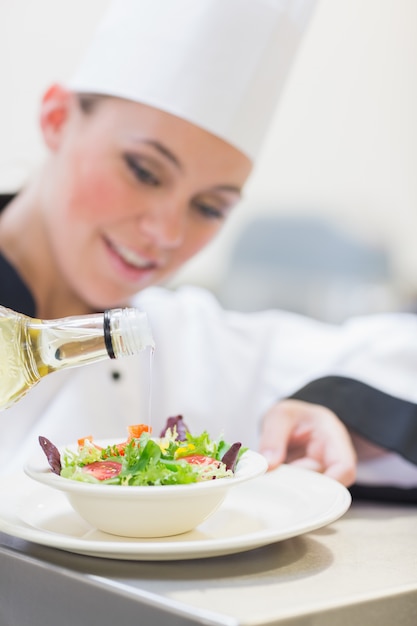 Foto chef versando olio d'oliva su insalata