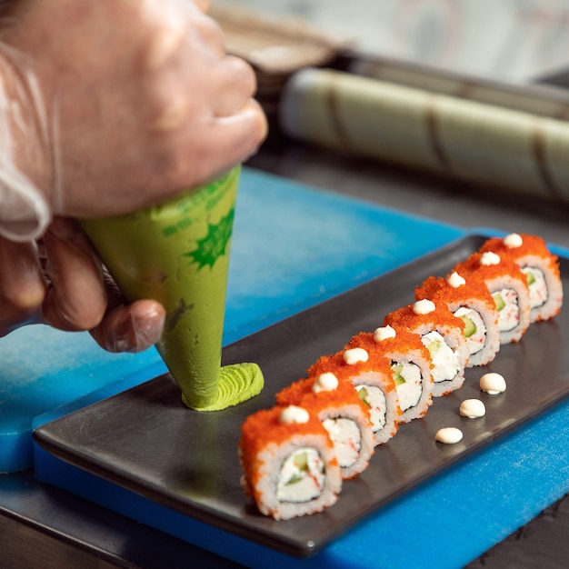 寿司テーブルにわさびを注ぐシェフ、カリフォルニアうなぎ巻き寿司