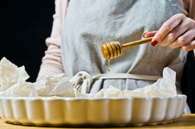 The chef pours honey slices of bananas in a baking dish. 